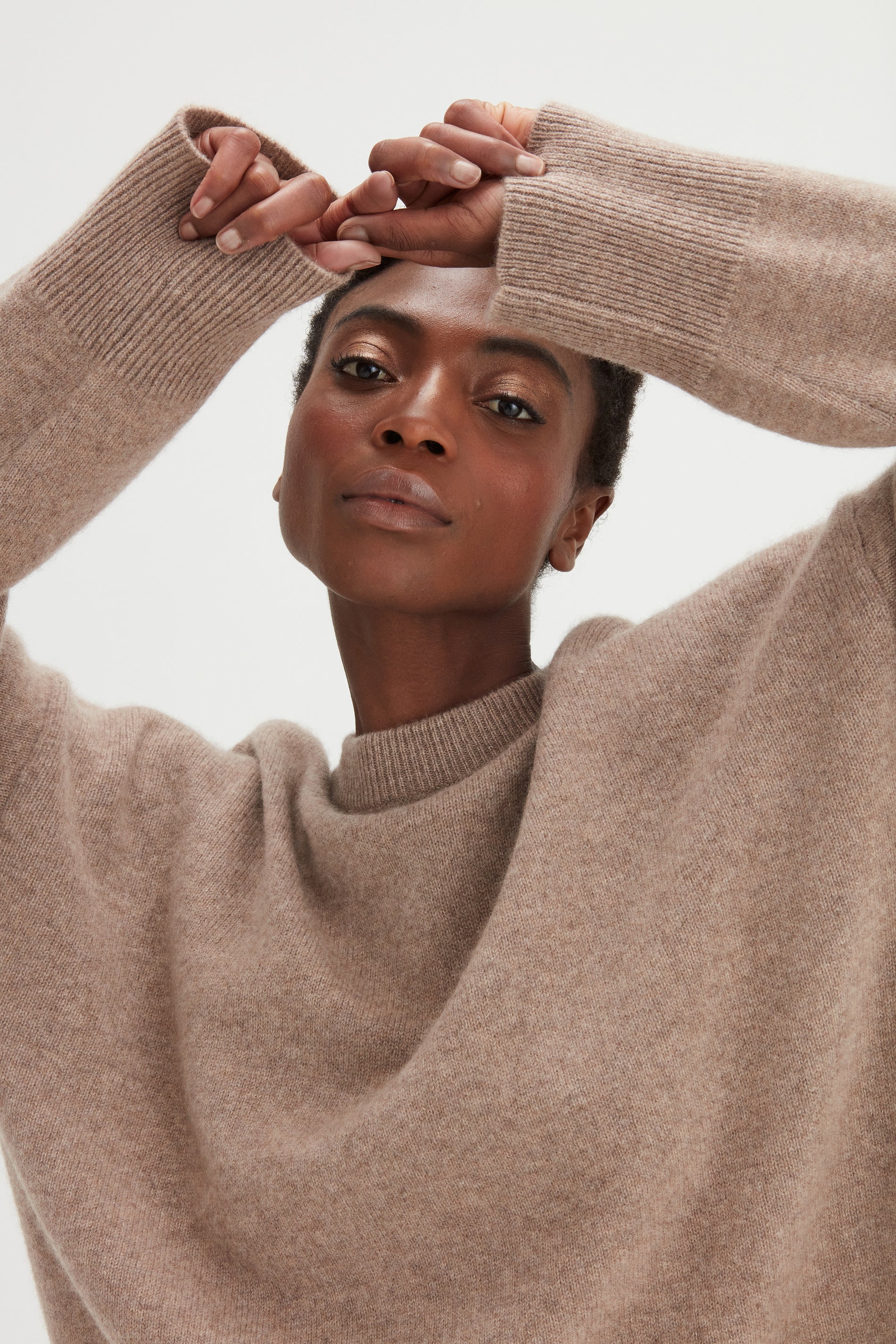 Woman wearing a beige sweater against a white background